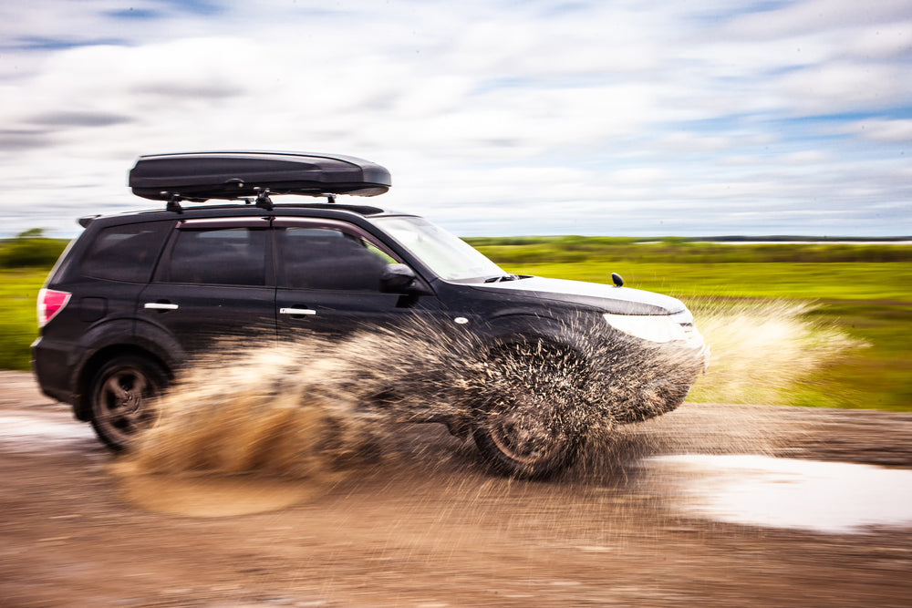 A 4WD with a roof rack storage moving on a muddy road